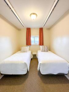 two beds in a room with a window at Oasis by the Bay Vacation Suites in Wasaga Beach