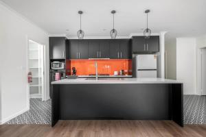 a kitchen with black and orange cabinets and a counter at Sensational New Townhouse in Canberra