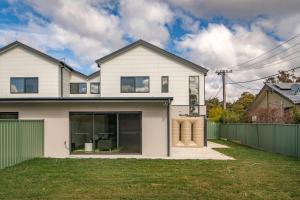 a white house with a green fence at Sensational New Townhouse in Canberra