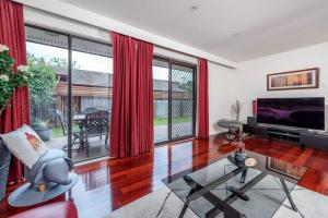 a living room with red drapes and a tv at Awesome family House & Studio in Narrabundah