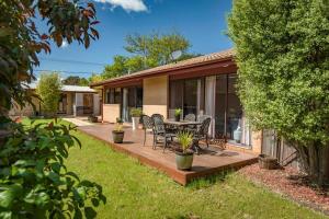 a house with a deck with a table and chairs at Awesome family House & Studio in Narrabundah