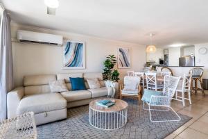 a living room with a couch and a table at Beachfront Oasis with Private Rooftop Retreat in Marcoola