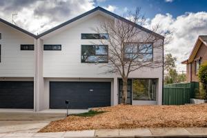 a white house with a tree and a garage at Gorgeous Hawker Townhouse in Canberra