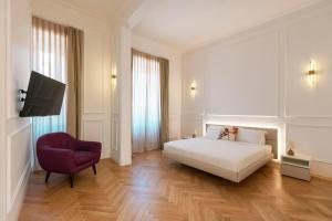 een slaapkamer met een wit bed en een rode stoel bij SJR Luxury Apartment Trevi Fountain in Rome