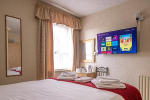 a bedroom with a bed with a tv on the wall at The Kildare in Skegness