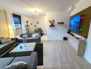 a living room with a couch and a tv on a wall at BesTime - 5 Schlafzimmer, Wohnzimmer, Küche, Waschtrockner, Terrasse, Smart-TVs, Netflix, Tischfußball in Wildeshausen