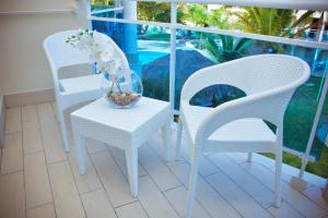 2 sillas blancas y una mesa con un plato de flores en el balcón en The Tropical at LHVC, Puerto Plata en San Felipe de Puerto Plata