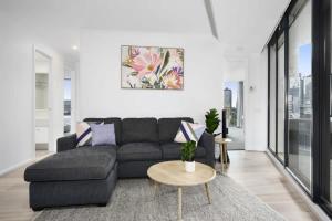 sala de estar con sofá negro y mesa en Modern Comfort Meets City Skyline, en Melbourne