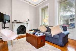 ein Wohnzimmer mit einem blauen Sofa und einem Kamin in der Unterkunft Charming Fitzroy Retreat Art, Dining, Serenity in Melbourne