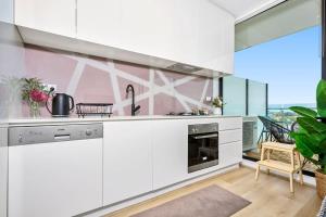 a kitchen with white cabinets and a large window at Stylish Urban Retreat with Spectacular Views and Prime Location in Melbourne