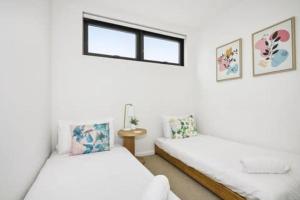 Duas camas num quarto branco com uma janela em Stylish Urban Retreat with Spectacular Views and Prime Location em Melbourne