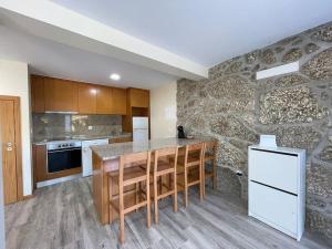 una cucina con un tavolo e un muro di pietra di Casa do Canastro a Terras de Bouro