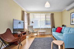 a living room with a blue couch and a tv at Ocean Blue Haven Beachside 2-Bed Unit in Hampton in Melbourne