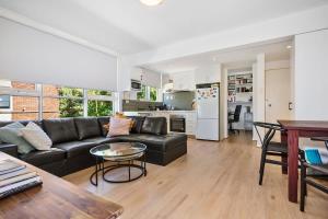 a living room with a black couch and a kitchen at Chic Elwood 1BR Apt with Free Parking in Melbourne