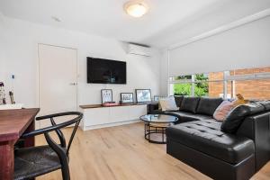 a living room with a black leather couch and a table at Chic Elwood 1BR Apt with Free Parking in Melbourne
