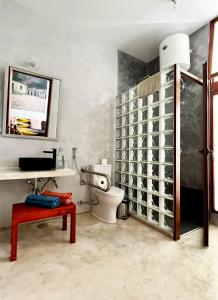 a bathroom with a toilet and a sink and a table at Casa de Poço Guest House and Gallery in Mindelo