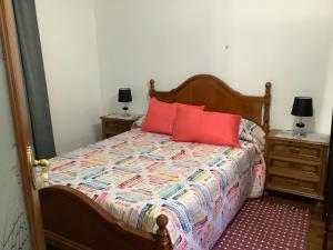 1 dormitorio con 1 cama con almohadas rojas y 2 mesitas de noche en Casita acogedora en el centro del pueblo en Porriño