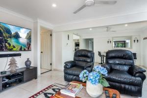 a living room with a leather chair and a couch at Seaside Serenity at Plumeria Place in Brisbane