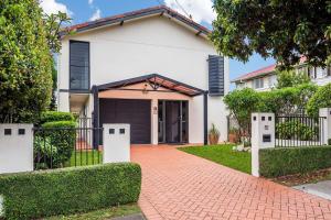 a white house with a gate and a driveway at Seaside Serenity at Plumeria Place in Brisbane