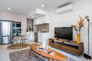 a living room with a large television and a table at Stylish Apartment with Rooftop Pool in Brisbane