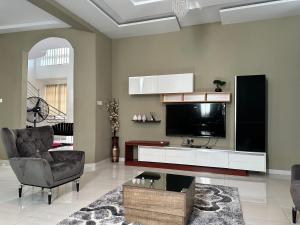 een woonkamer met een tv en een bank en een stoel bij Nanani Villa - Harmonious Paradise in Kumasi