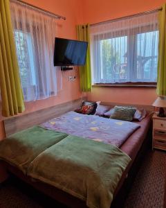 a bedroom with a bed and a flat screen tv at Dom Pod Różami Agroturystyka in Srebrna Góra
