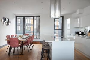 a kitchen and dining room with a table and chairs at Canning Town by Viridian Apartments in London