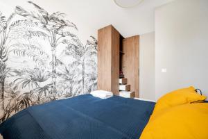 a bedroom with a blue bed with a tropical wallpaper at Wieniawskiego Chic Apartment in Łódź