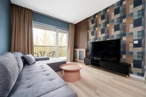 a living room with a couch and a flat screen tv at Wieniawskiego Chic Apartment in Łódź