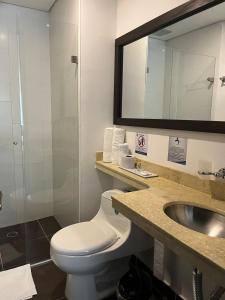 ein Badezimmer mit einem WC, einem Waschbecken und einem Spiegel in der Unterkunft Hotel H53 in Sogamoso