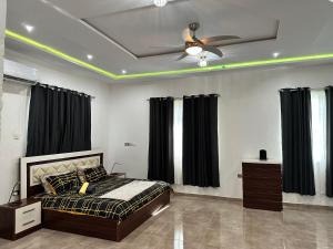 een slaapkamer met een bed en een plafondventilator bij Nanani Villa - Harmonious Paradise in Kumasi