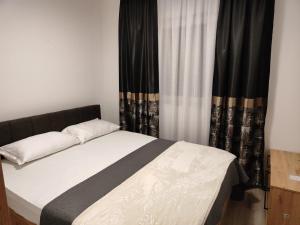 Bett in einem Schlafzimmer mit schwarzen Vorhängen in der Unterkunft Apartmani Sanja in Teslić