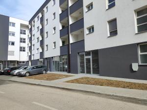 ein Gebäude mit Autos auf einem Parkplatz in der Unterkunft Apartmani Sanja in Teslić