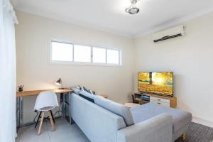 sala de estar con sofá azul y TV en Modern 2BR With Deck en Brisbane