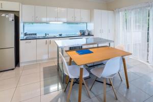 a kitchen with a wooden table and white cabinets at Modern 2BR With Deck in Brisbane