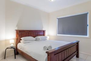 a bedroom with a large bed with white sheets and a window at Modern 2BR With Deck in Brisbane