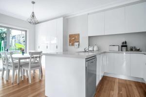 una cucina bianca con tavolo e sedie di Stylish Home in the heart of Newtown a Sydney