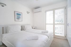 a white bedroom with two beds and a window at Stylish Home in the heart of Newtown in Sydney