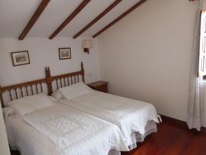 a bedroom with a bed with white sheets and a window at Montañes in Santillana del Mar