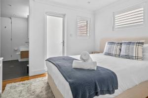 a white bedroom with a bed with a towel on it at Rodd Point Luxury Haven: Waterfront Elegance with BBQ Terrace in Sydney