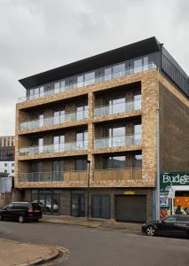 um grande edifício de tijolos com carros estacionados em frente em Canning Town by Viridian Apartments em Londres