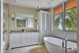 a white bathroom with a tub and a mirror at Oil Nut Bay in Virgin Gorda