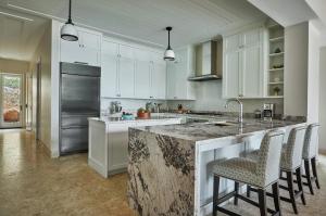 a kitchen with white cabinets and a island with bar stools at Oil Nut Bay in Virgin Gorda