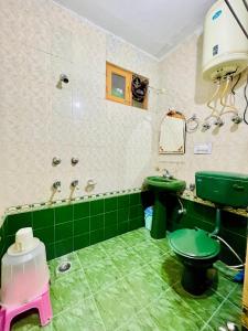 baño con aseo verde y lavamanos en Grand view lodge and Restaurant Dharamshala en Dharamshala