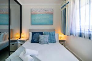 1 dormitorio con 1 cama blanca grande con almohadas azules en Large Private Terrace - North Facing Terrace & BBQ, en Deewhy