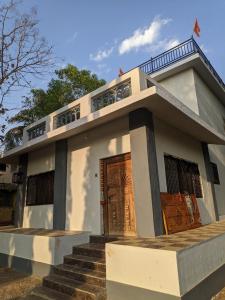 a small white house with a brown door at White House at Bhadane Saralgaon in Saralgaon