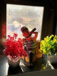 a figurine sitting next to two flowers on a table at White House at Bhadane Saralgaon in Saralgaon