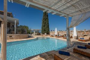 una piscina con pergolato accanto a una casa di Louiza - Luxury Stone Villa a Volímai