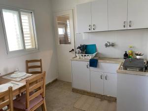 una cucina con armadi bianchi, tavolo e finestra di Cozy apartment on the beach a Haifa