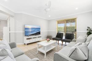 a living room with white furniture and a flat screen tv at 'Sanctuary On Walmer' - Sanctuary Point NSW in Sanctuary Point